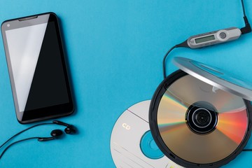 personal cd player with remote control and modern smartphone on blue background