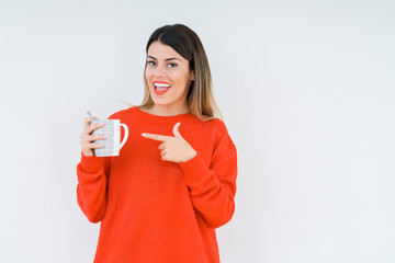 Young woman drinking cup of coffee over isolated background very happy pointing with hand and finger