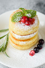 Tasty fresh cottage cheese pancakes on a white plate with a glass of milk on a concrete background. Healthy and diet breakfast