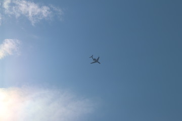 A passenger airplane flying high in the sky among the clouds. Air liner leaving a trace of exhaust gases glowing in the sun. Ecology of passenger traffic. Transport of goods by air