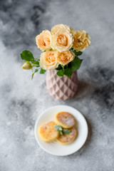 Beautiful fresh flowers in a vase and sweet on a plate on a table. It can be used as a background
