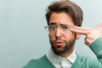 Young handsome entrepreneur man face closeup making a suicide gesture, feeling sad and scared...