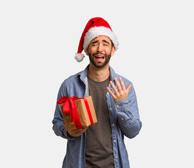 Young man wearing santa hat very scared and afraid
