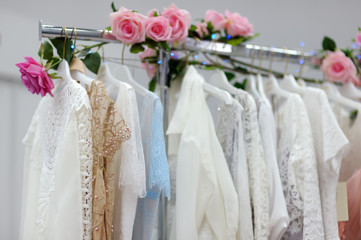 Few beautiful wedding, bridesmaid or evening dresses or ball gown on a hanger in a bridal shop