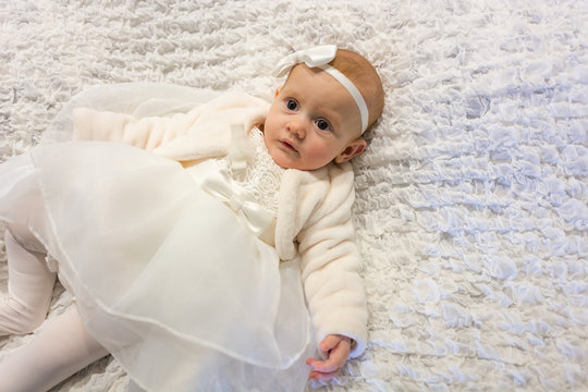 beautiful baby girl on baptism day with white dress and bow