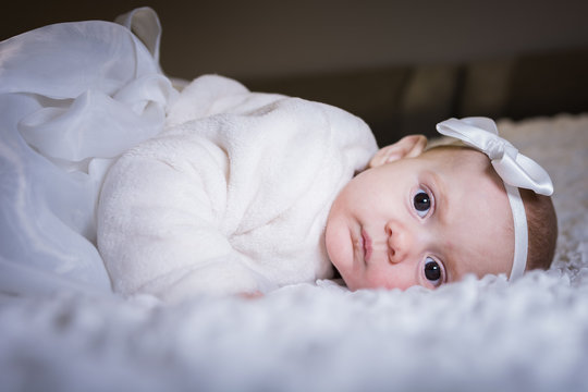 beautiful baby girl on baptism day with white dress and bow