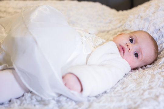 beautiful baby girl on baptism day with white dress and bow