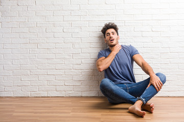 Young natural man sit on a wooden floor worried and overwhelmed, anxious feeling pressure, concept of anguish