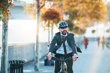Schilderijen op glas Hipster businessman commuter with electric bicycle traveling home from work in city. © Halfpoint