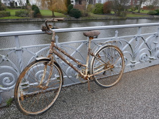 Fototapeta na wymiar Old rusty lady's bicycle, parked at a bridge railing and then forgotten