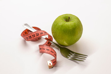 Diet. Apple and centimeter. Fitness healthy eating. Apple and measuring tape tied around fork with copy space on white background. Weight loss concept on white background. Diet Healthy.