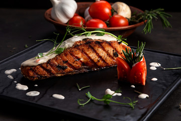 Grilled Salmon Steak with Vegetables on black background.