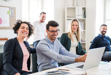 Group of young businesspeople around table in a modern office, having meeting.