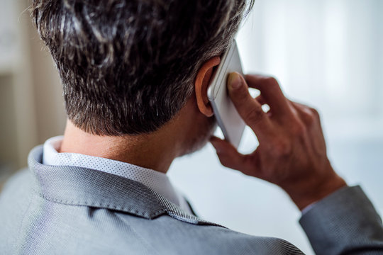 A Rear View Of Mature Businessman With Smartphone Making A Phone Call.