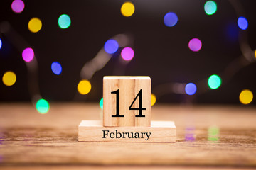 February 14th. Day 14 of february month set on wooden calendar at center of dark background with garland bokeh. Winter time. Empty space for text, mockup. Valentines Day. Day geek. 