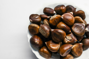 Chestnuts on a blank (white) background. Pile of fresh chestnuts ready to roast shot over white background