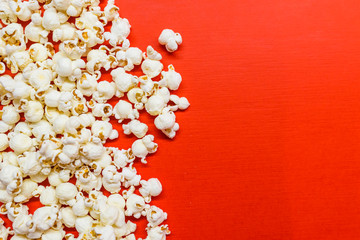 Tasty salted popcorn isolated on red background. Popcorn border isolated on red, clipping path included. Cinema, movies and entertainment concept. - obrazy, fototapety, plakaty