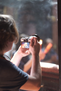 A young man with a camera in his hands is taking pictures in a Buddhist temple