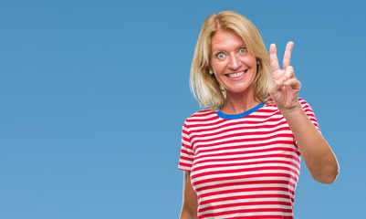 Fototapeta premium Middle age blonde woman over isolated background smiling with happy face winking at the camera doing victory sign. Number two.