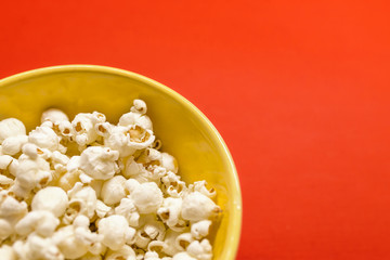 Tasty salted popcorn in bowl isolated on red background. Popcorn border isolated on red, clipping path included. Cinema, movies and entertainment concept.