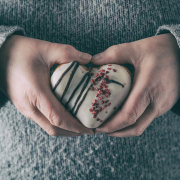 female hands that hold Donut in the shape of a heart- Valentines day concept, selective focus. 