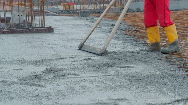 Video of an unrecognised worker levelling concrete with a rake on a construction site