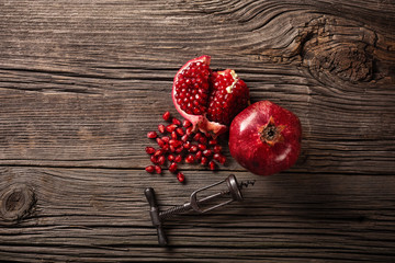 Ripe pomegranate fruit and a corkscrew on a wooden background