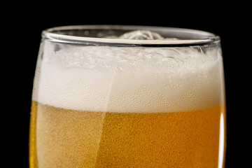 Glass of light beer on a black background, close-up
