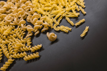 Variety of types of Italian pasta background. Set of raw dry pasta on a black slate background.