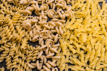 Variety of types and shapes of dry Italian pasta. Set of raw dry pasta on a black slate background.