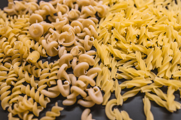 Variety of types and shapes of dry Italian pasta. Set of raw dry pasta on a black slate background.