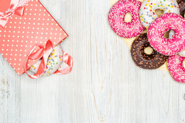 Donuts and gift bag with donuts inside on a wooden table. Flat lay. Copy space. The concept of holiday and gifts