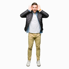 Fototapeta premium Handsome man wearing winter coat Trying to hear both hands on ear gesture, curious for gossip. Hearing problem, deaf