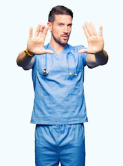 Naklejka premium Handsome doctor man wearing medical uniform over isolated background Smiling doing frame using hands palms and fingers, camera perspective