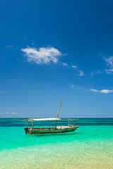 Fototapeta premium alone boat with white roof in emerald water under blue sky with little cloud in Zanzibar in Tanzania
