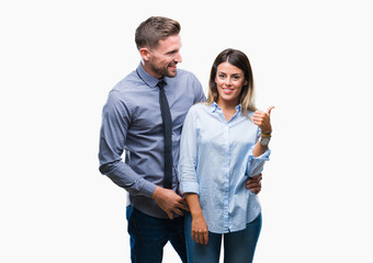 Young workers business couple over isolated background smiling with happy face looking and pointing to the side with thumb up.