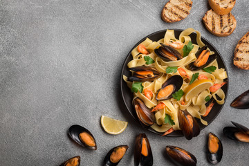 Tasty pasta with mussels, squid, parsley and lemon, top view.