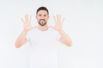Young handsome man wearing casual white t-shirt over isolated background showing and pointing up with fingers number ten while smiling confident and happy.