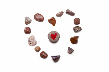 A heart made with pebbles, with a pebble with a red heart painted on it in the center