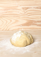 Homemade dough with flour on wooden background. Dough on the background with a place for copispeysa. Homemade cakes, bread, dumplings, dumplings