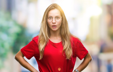 Young beautiful blonde woman wearing glasses over isolated background afraid and shocked with surprise expression, fear and excited face.