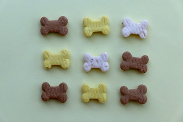 Obraz premium Dog treats, shaped like small bones, arranged on a pastel green background. 