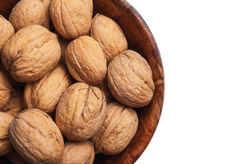 Walnuts in wooden bowl isolated on white studio background. Whole nuts in shells in round container with empty copy space for graphic design text.