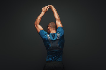 Hard work will solve your problems. Sportsman is stretching standing over dark background
