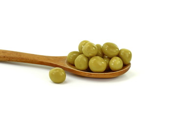 Canned green peas in a wooden spoon isolated on white background