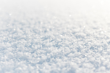 Fresh fluffy snow on the ground sparkle in the sun. Low angle closeup view with perspective and...