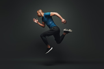 Jump higher! Sportsman jumping over dark background