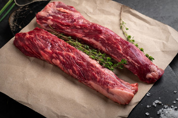 two raw beef steaks lie on crafting paper on a wooden Board