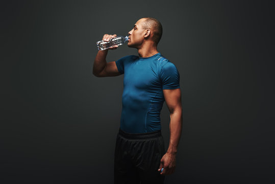 Hydrating. Muscular sportsman drinking water after training - Powered by Adobe
