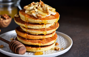 Homemade, hot pancakes with banana, honey and nuts on the kitchen table.